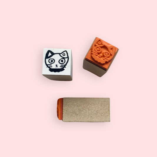 Tiny Calico Mike-chan Cat Head Rubber Stamp with black cat face design and orange rubber stamp on pink background
