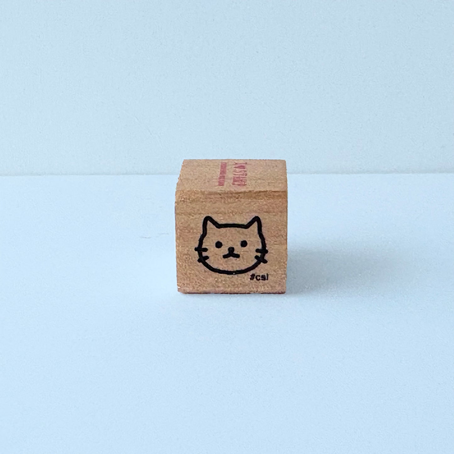 Small wooden block with a cat illustration on a light blue background