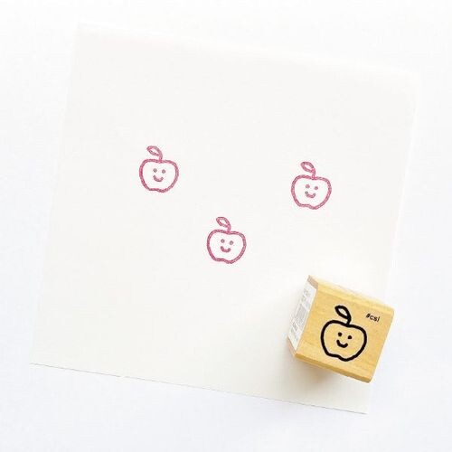 Little Happy Apple Rubber Stamp showing three red apple faces stamped on white paper with wooden stamp block nearby
