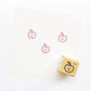 Little Happy Apple Rubber Stamp showing three red apple faces stamped on white paper with wooden stamp block nearby