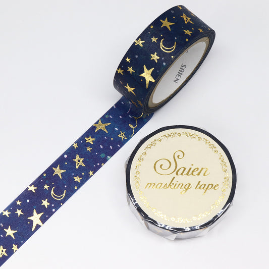 Roll of blue masking tape with gold star and moon pattern on a white background