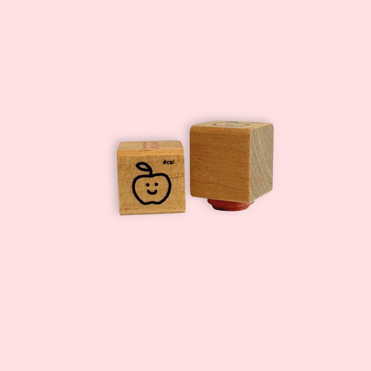 Little Happy Apple Rubber Stamp with wooden block and smiling apple design on pink background.