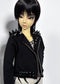 A doll with short black hair and pale skin wearing a black studded jacket with black metal details, photographed against a plain light background.