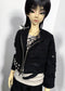 A doll wearing a black distressed zip-front jacket with silver studs and spikes, layered over a light gray top and black bottoms, photographed against a plain light background.