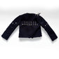 A black studded jacket with distressed details and silver spikes on the shoulders, displayed against a light gray background.