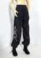 Dark gray heathered sweatpants with a white geometric line graphic on the lower left leg, shown on a doll wearing black lace-up boots against a white studio background.