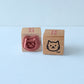 Two wooden stamps with cat designs on a light blue background