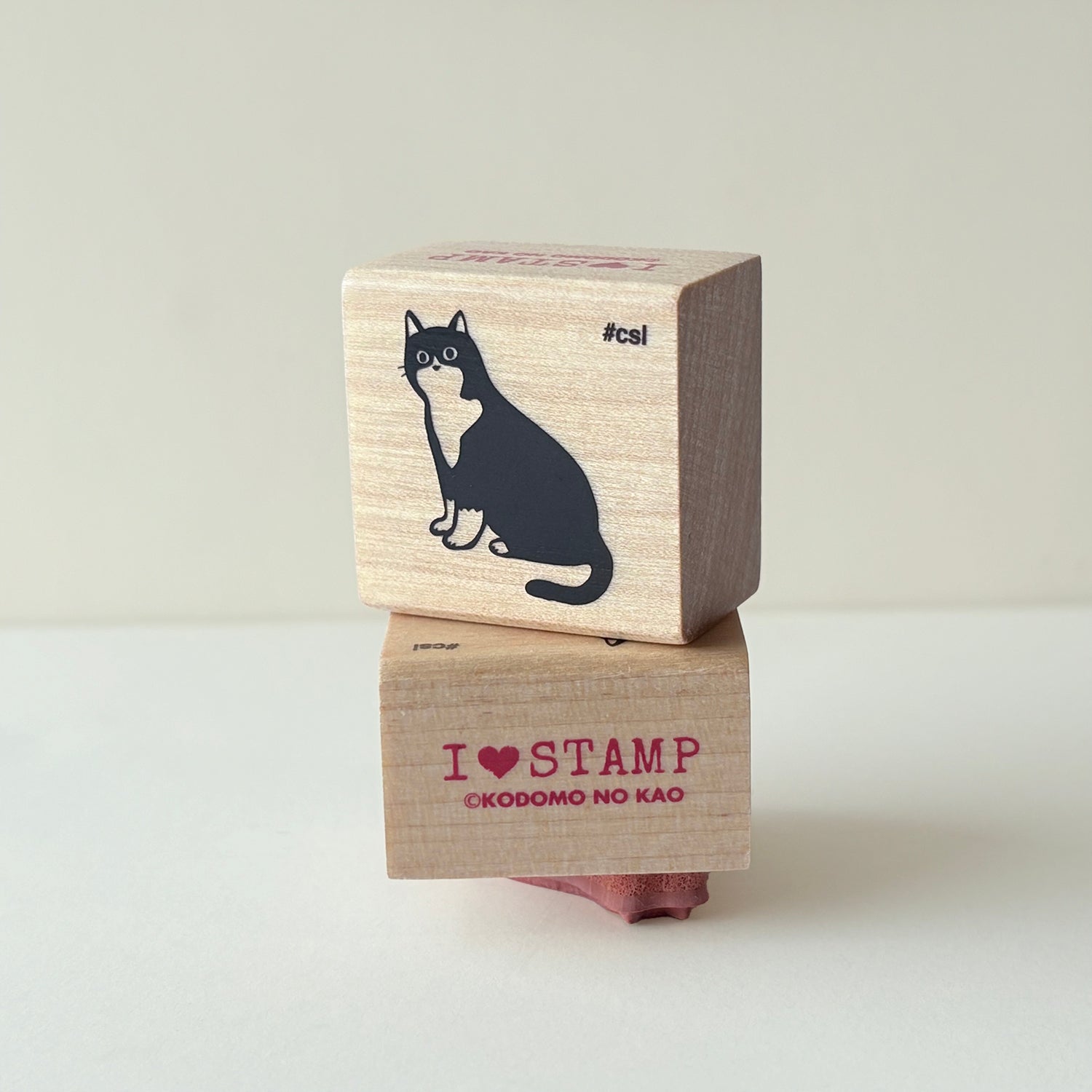 Two wooden stamps with a sitting cat design and brand name text on a light background